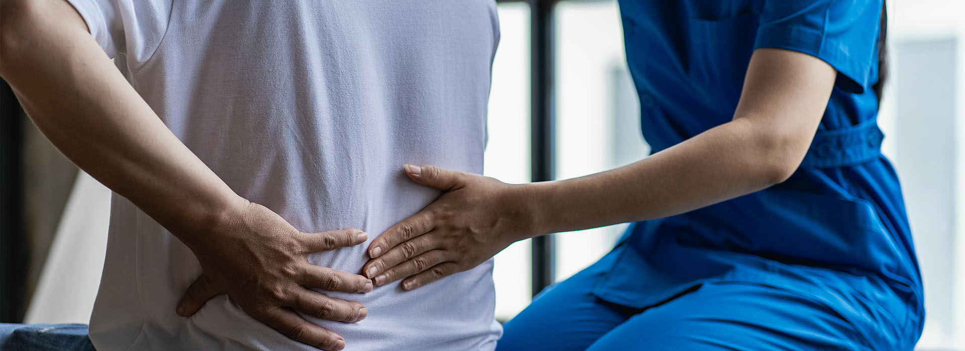 A medical professional in blue scrubs providing an ultrasound to a patient lying on their back.