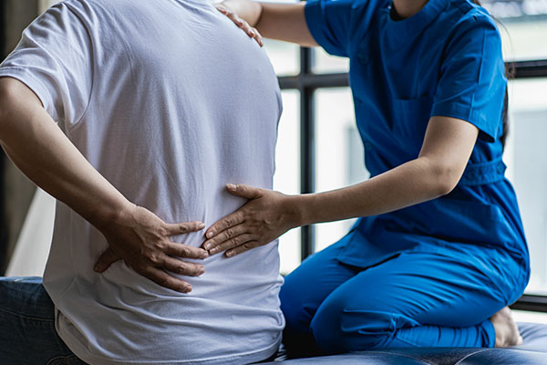 Physician performing chiropractic adjustment on patient, both in blue scrubs.