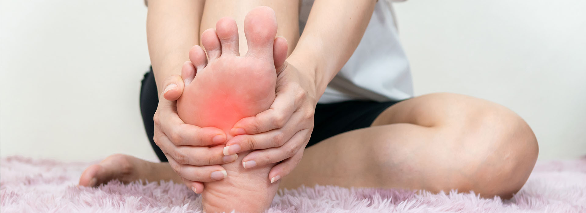 The image shows a person sitting on the floor with their leg extended, displaying a red inflammation or sore area near the ankle.